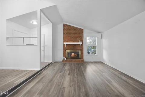an empty room with windows a fireplace and wooden floor