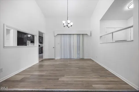 a view of an empty room with wooden floor fireplace and a window