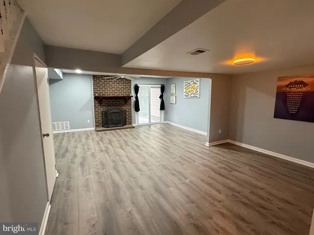 a view of empty room with wooden floor and fireplace