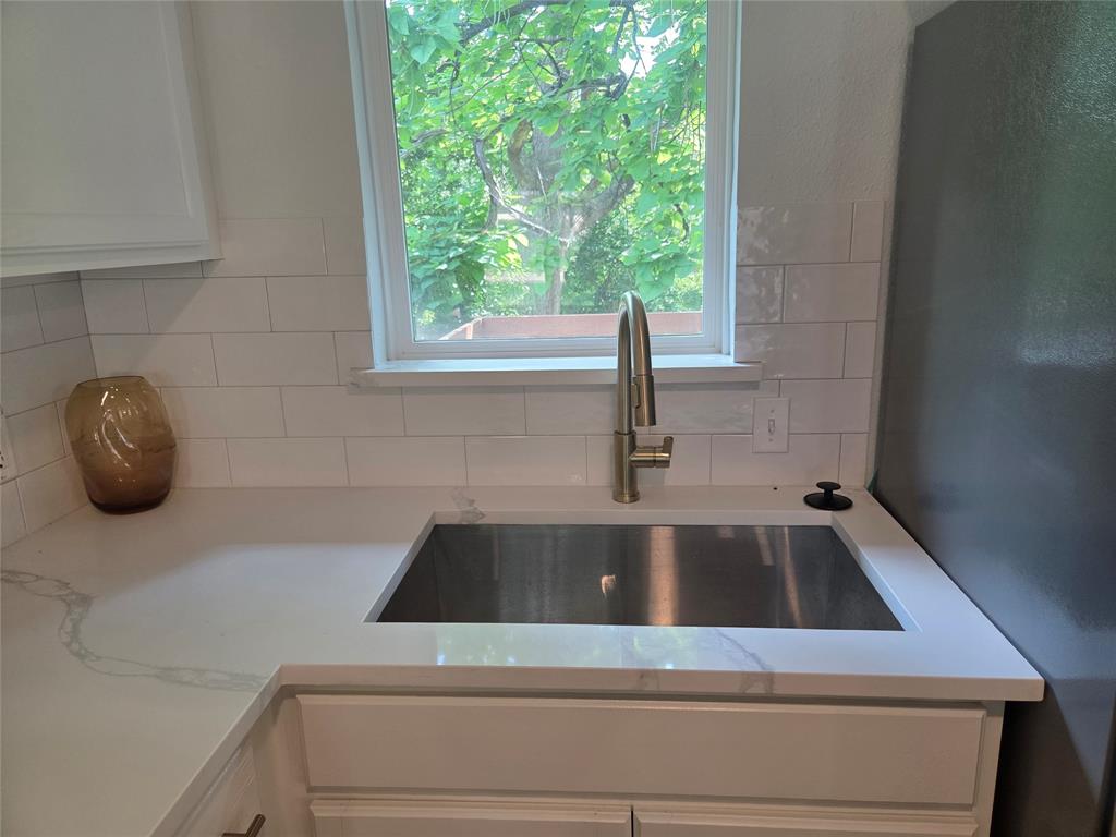2108 Blake Avenue Dallas, TX 75228 - Photo 4 of 13 Kitchen workstation featuring a stainless steel undermount sink, gooseneck faucet, white subway tile backsplash, and white countertops with subtle veining