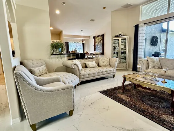 a living room with furniture kitchen view and a chandelier