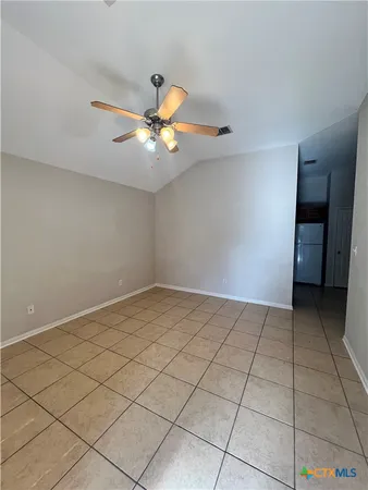 a view of an empty room and chandelier fan