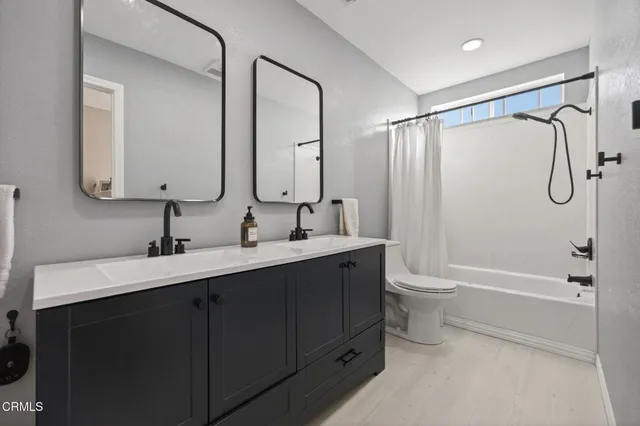 a bathroom with a double vanity sink toilet mirror and bathtub