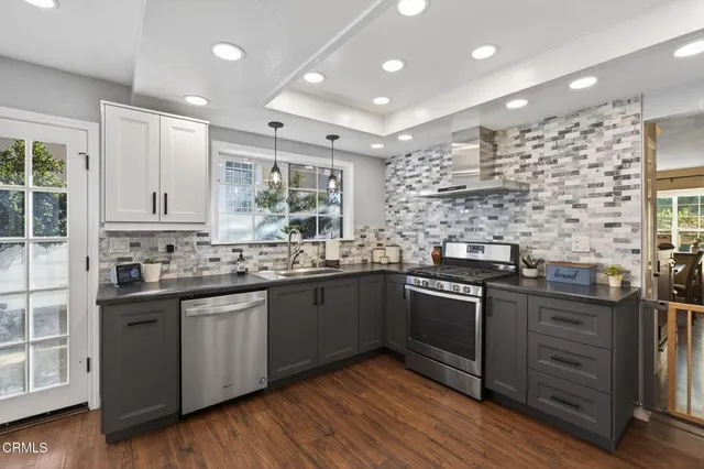 a kitchen with stainless steel appliances kitchen island granite countertop a sink cabinets and wooden floor