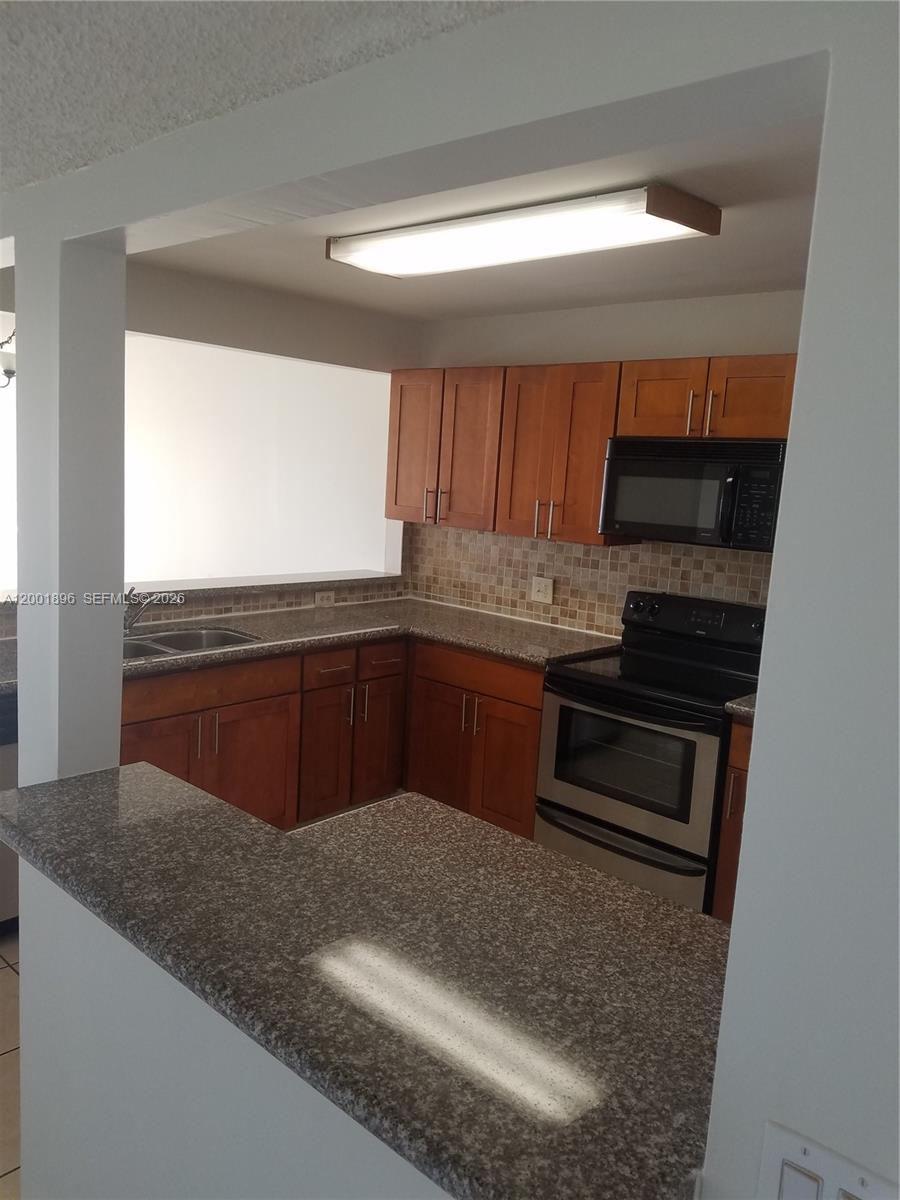 310 Racquet Club Road, Unit 204 Weston, FL 33326 - Photo 3 of 22 a kitchen with stainless steel appliances kitchen island granite countertop a stove a sink and a microwave