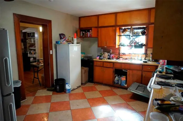 a room with a black white checkered floor with a gaming machine and stainless steel appliances