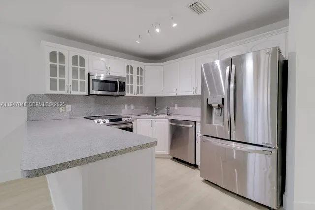 a kitchen with refrigerator a microwave a stove and cabinets