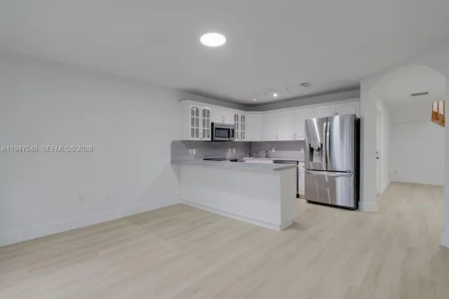 a kitchen with stainless steel appliances a refrigerator sink and white cabinets