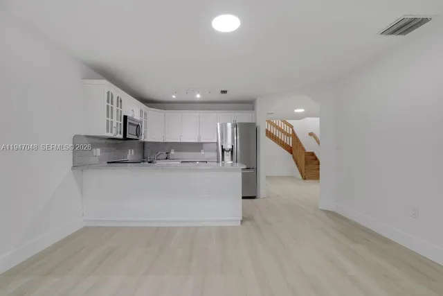 a view of kitchen with stainless steel appliances granite countertop cabinets and wooden floor