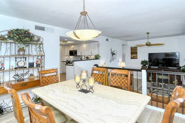 a kitchen with stainless steel appliances kitchen island granite countertop a table chairs and a wooden floor