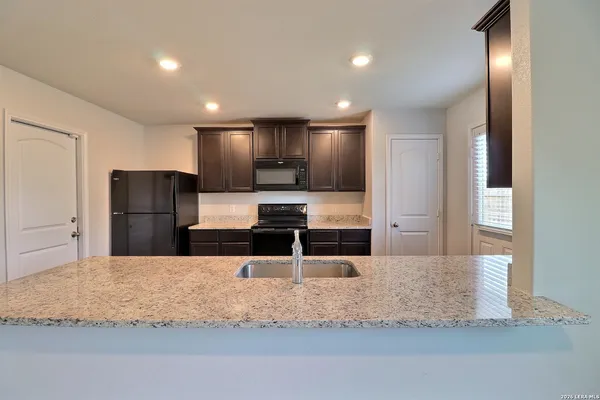 a kitchen with stainless steel appliances kitchen island granite countertop a refrigerator and a sink
