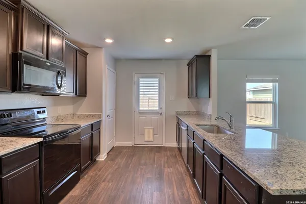 a kitchen with granite countertop cabinets stainless steel appliances a sink and wooden floor