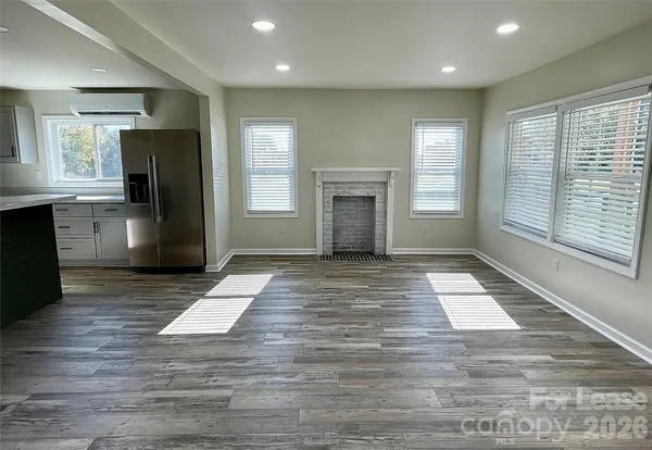 a view of an empty room with a kitchen and a window