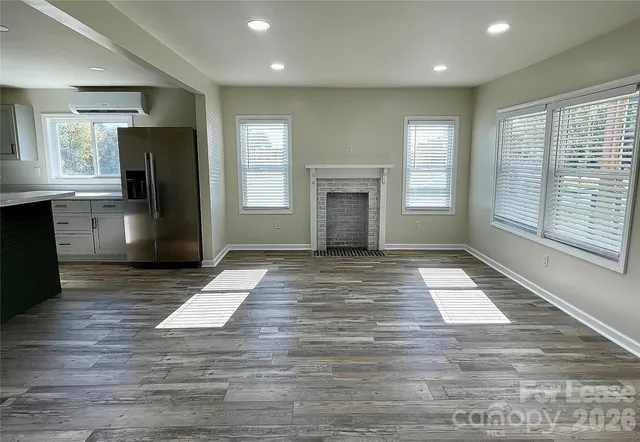 a view of an empty room with a kitchen and a window