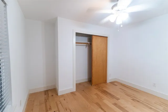 an empty room with closet and a ceiling fan