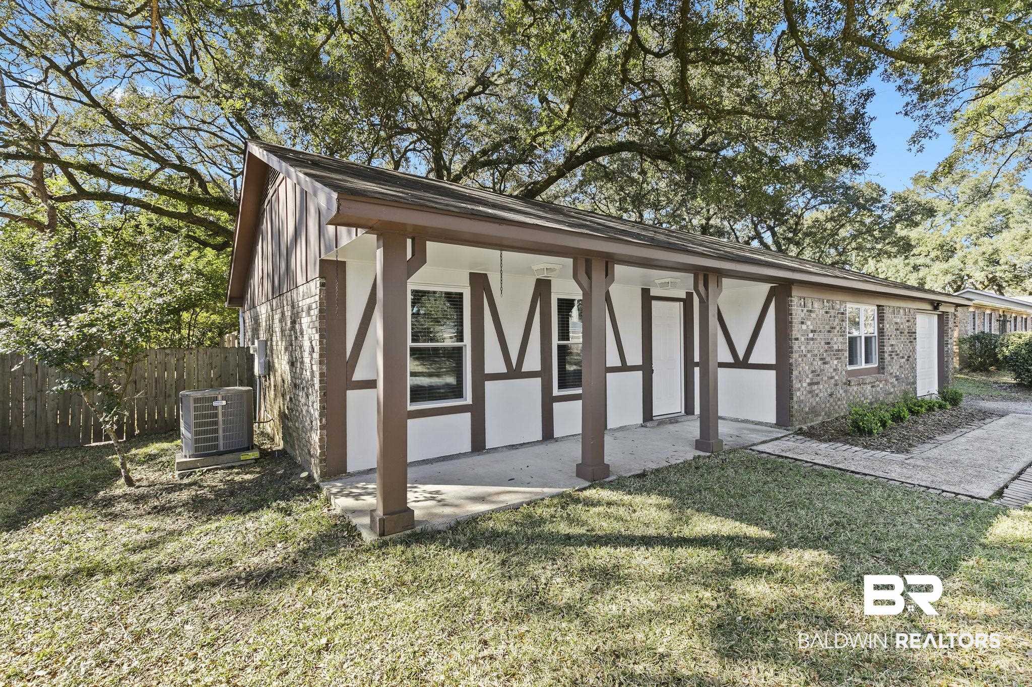 5817 Woodgate Road Mobile, AL 36609 - Photo 5 of 85 View of front of home with stucco siding, fence, a front lawn, central AC, and brick siding