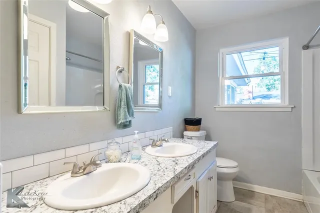 a bathroom with a granite countertop sink toilet and a mirror