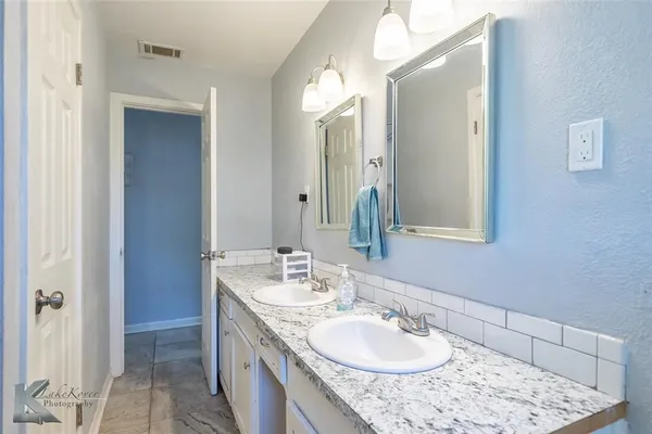 a bathroom with a granite countertop sink double and mirror