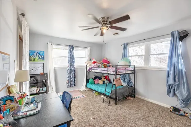 a room with chandelier fan and windows