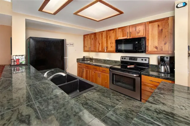 a kitchen with granite countertop a sink and steel appliances