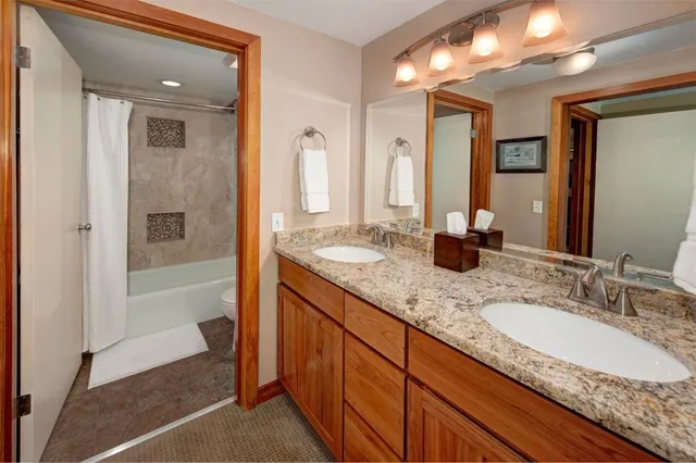 a bathroom with a granite countertop double vanity sink and a mirror