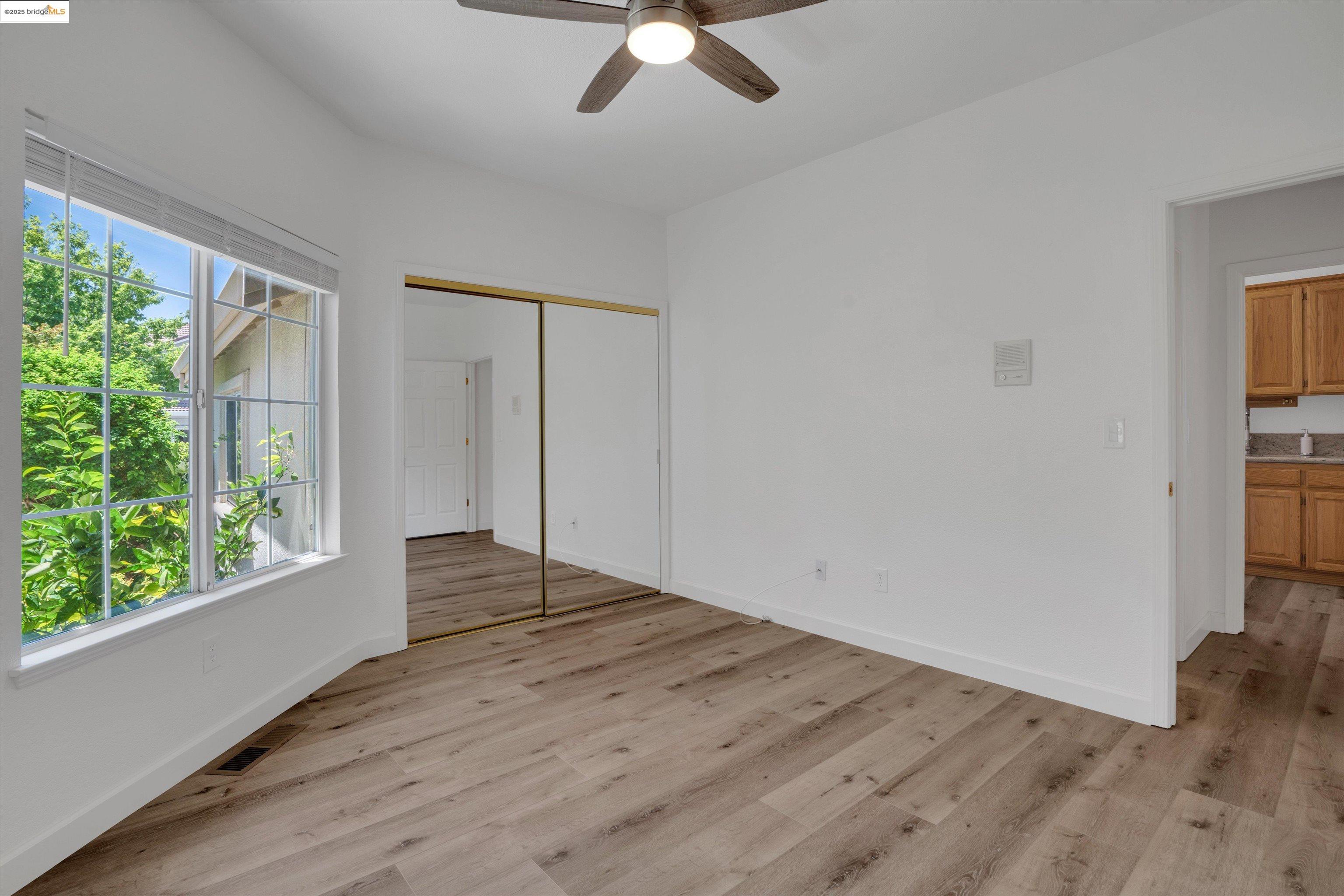805 Devonshire Loop Brentwood, CA 94513 - Photo 17 of 51 an empty room with wooden floor chandelier fan and windows