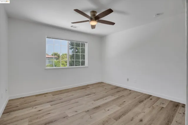 an empty room with wooden floor and ceiling fan
