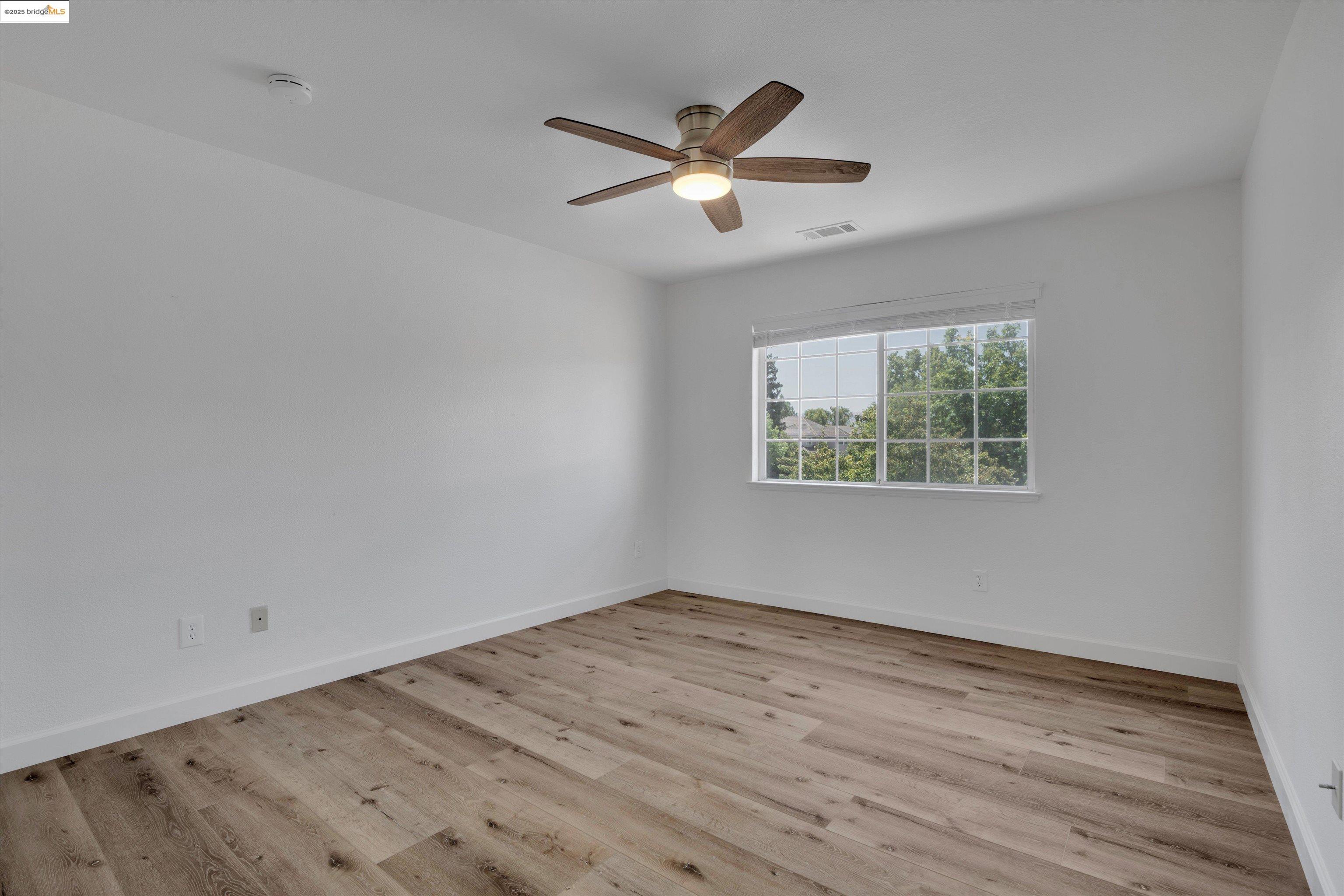 805 Devonshire Loop Brentwood, CA 94513 - Photo 22 of 51 an empty room with wooden floor ceiling fan and windows