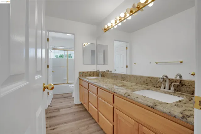 a bathroom with a granite countertop sink a large mirror and shower