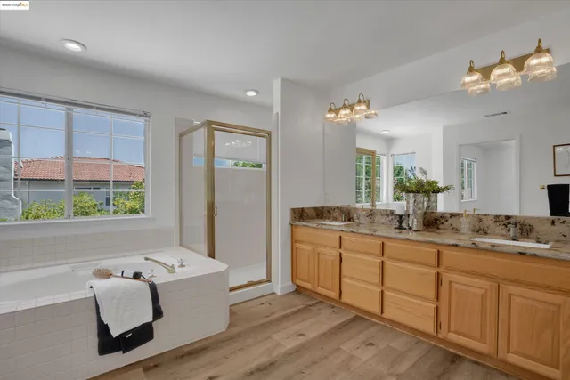 a spacious bathroom with a double vanity sink large mirror and a bathtub