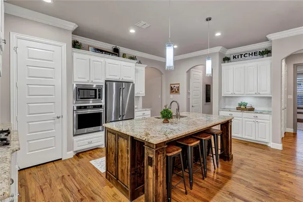 a kitchen with stainless steel appliances a dining table chairs refrigerator and microwave