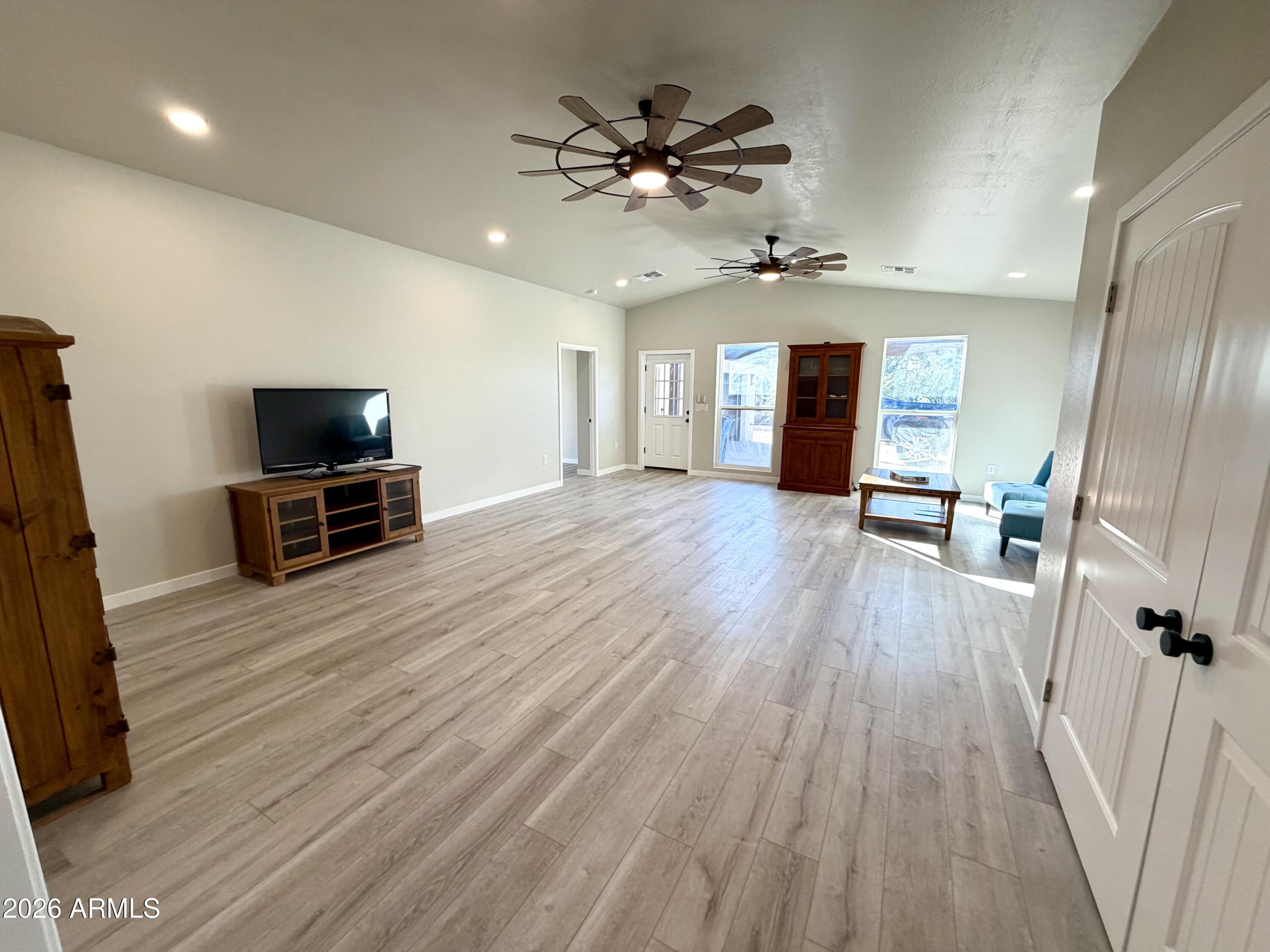 1165 North Mountain View Road Apache Junction, AZ 85119 - Photo 9 of 29 an empty room with wooden floor and a ceiling fan
