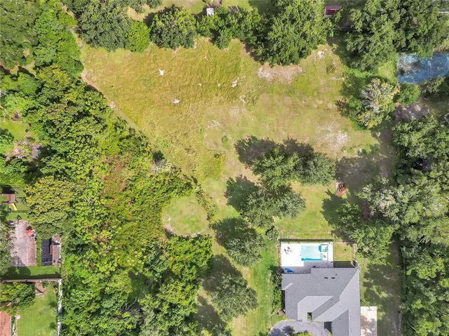 an aerial view of residential houses with outdoor space and trees