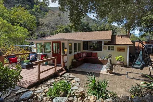 a view of a patio with couches table and chairs under an umbrella