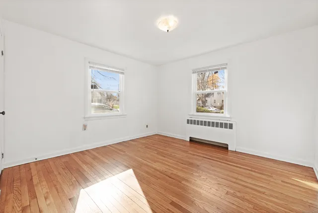 a view of a bedroom with wooden floor and window
