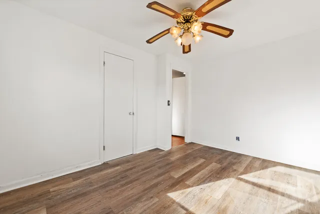 a view of a big room with wooden floor and a chandelier fan