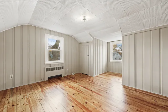 a view of a bedroom with wooden floor and windows