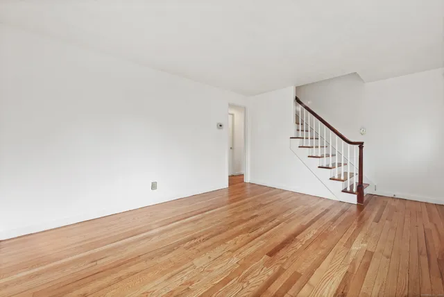 a view of an empty room with wooden floor and stairs