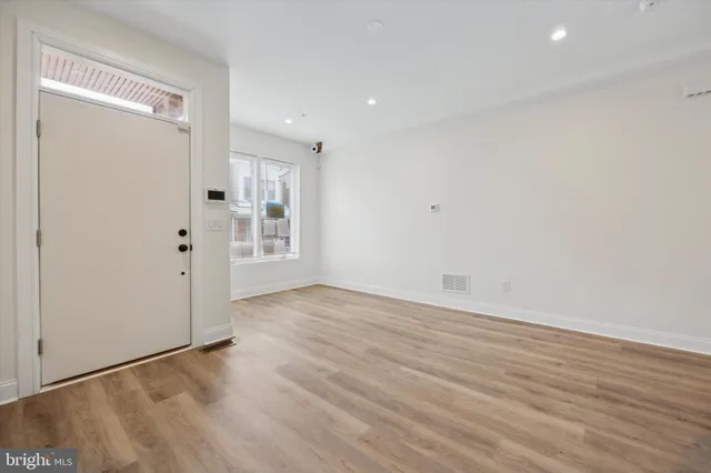 a view of an empty room with wooden floor and window