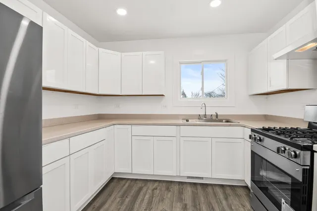 a kitchen with stainless steel appliances granite countertop a sink and cabinets with wooden floor