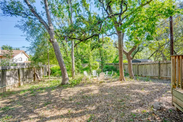 a backyard of a house with lots of plants and large trees