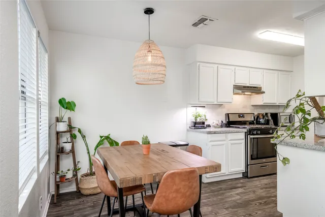 a kitchen with stainless steel appliances granite countertop a stove top oven a sink a dining table and chairs with wooden floor