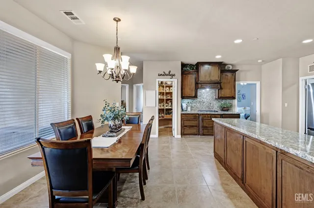 a kitchen with stainless steel appliances granite countertop a refrigerator a sink dishwasher a dining table and chairs with wooden floor