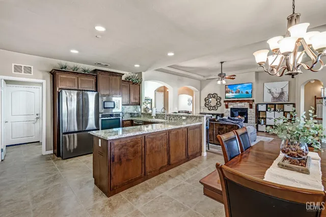 a kitchen with stainless steel appliances granite countertop a stove top oven a sink dishwasher a dining table and chairs with wooden floor