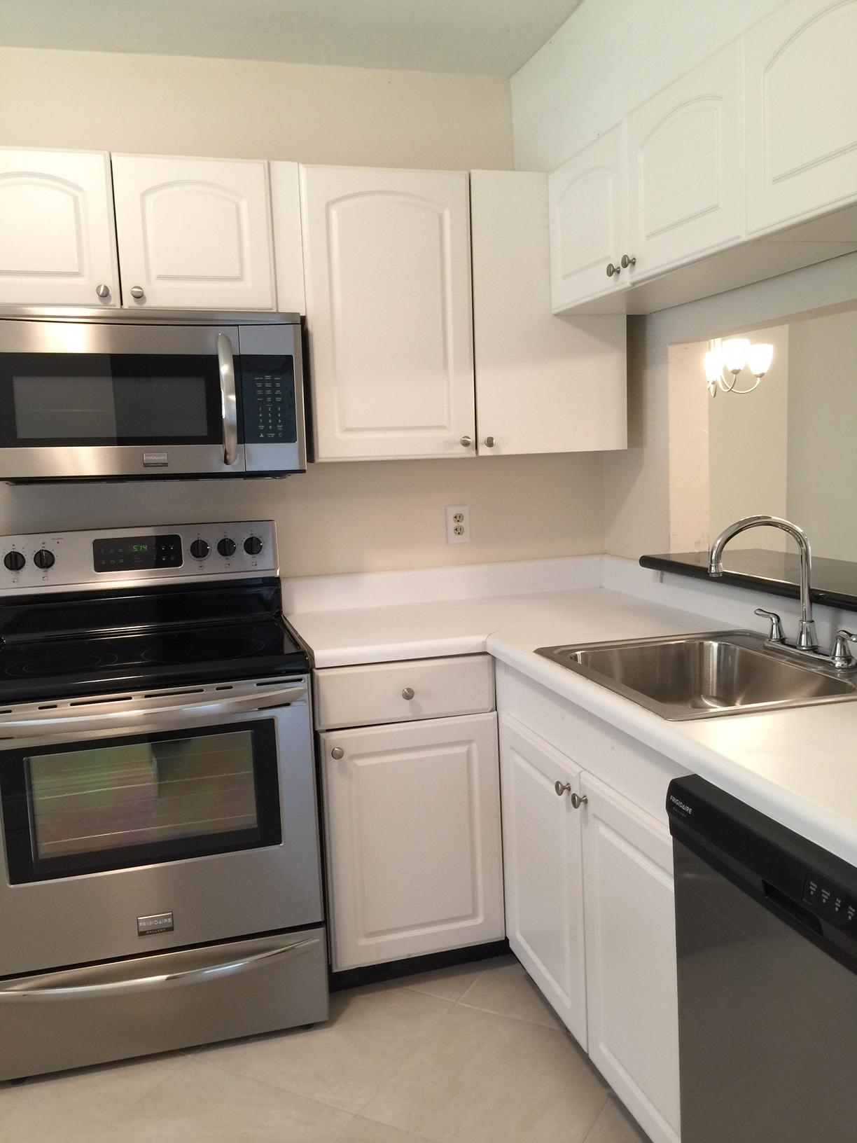 6772 Palmetto Circle South, Unit 104 Boca Raton, FL 33433 - Photo 4 of 17 a kitchen with granite countertop white cabinets and stainless steel appliances