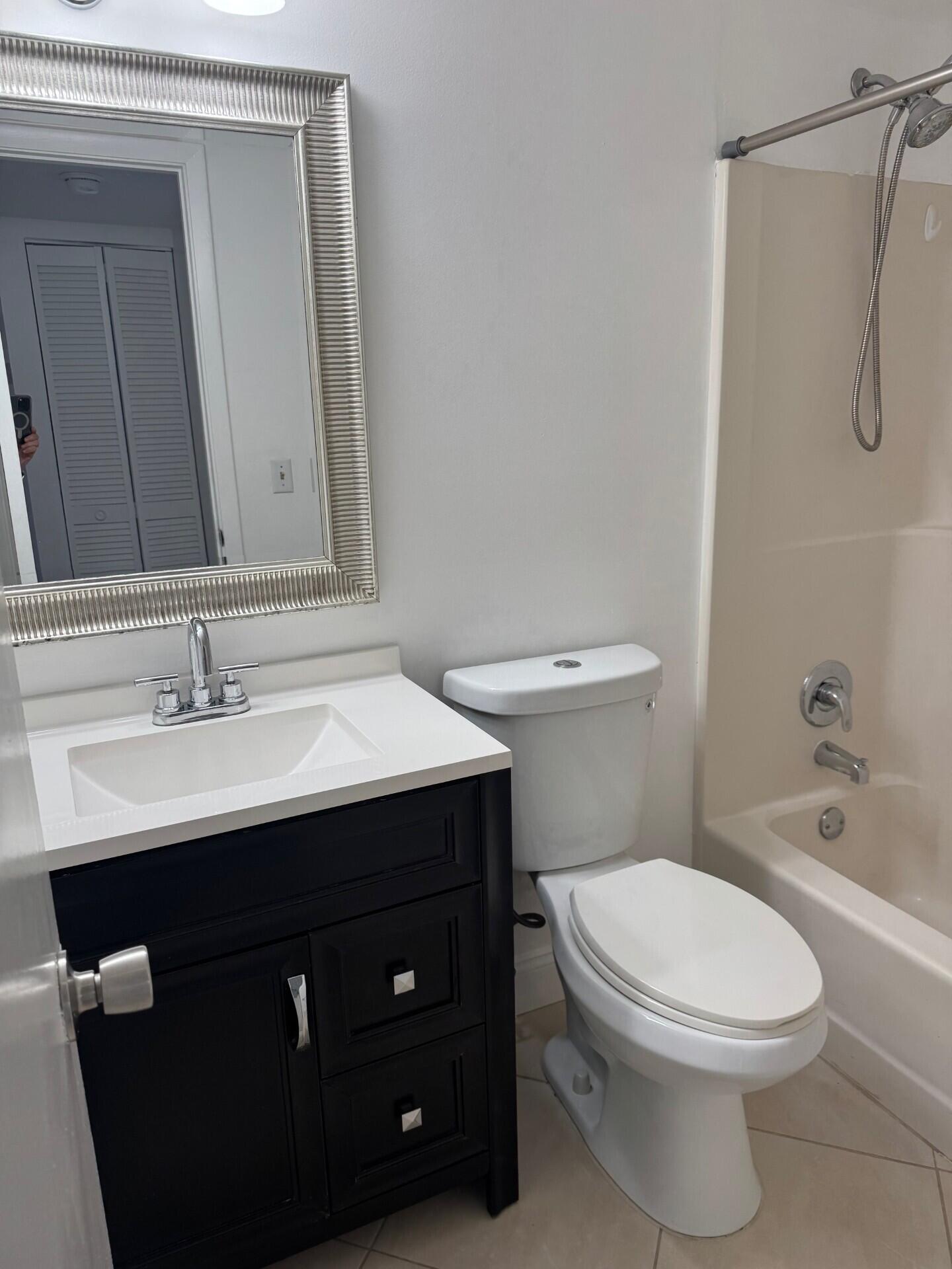 6772 Palmetto Circle South, Unit 104 Boca Raton, FL 33433 - Photo 5 of 17 a bathroom with a sink a toilet and shower