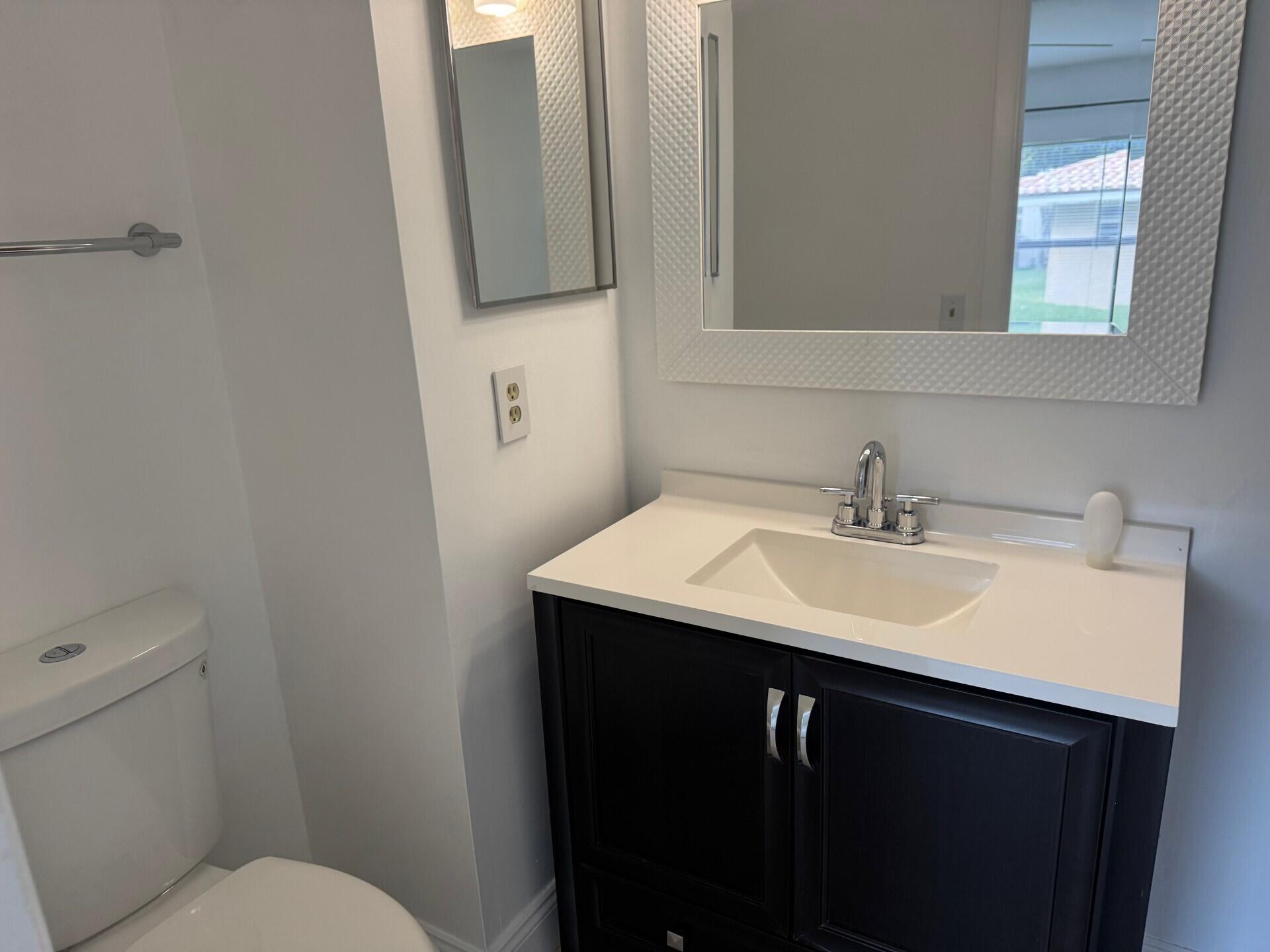 6772 Palmetto Circle South, Unit 104 Boca Raton, FL 33433 - Photo 10 of 17 a bathroom with a sink toilet and mirror