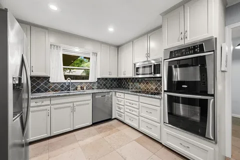 a kitchen with stainless steel appliances granite countertop a stove microwave and cabinets