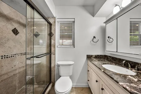 a bathroom with a granite countertop sink toilet and shower