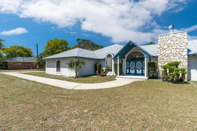 a view of a white house with a yard and wooden fence